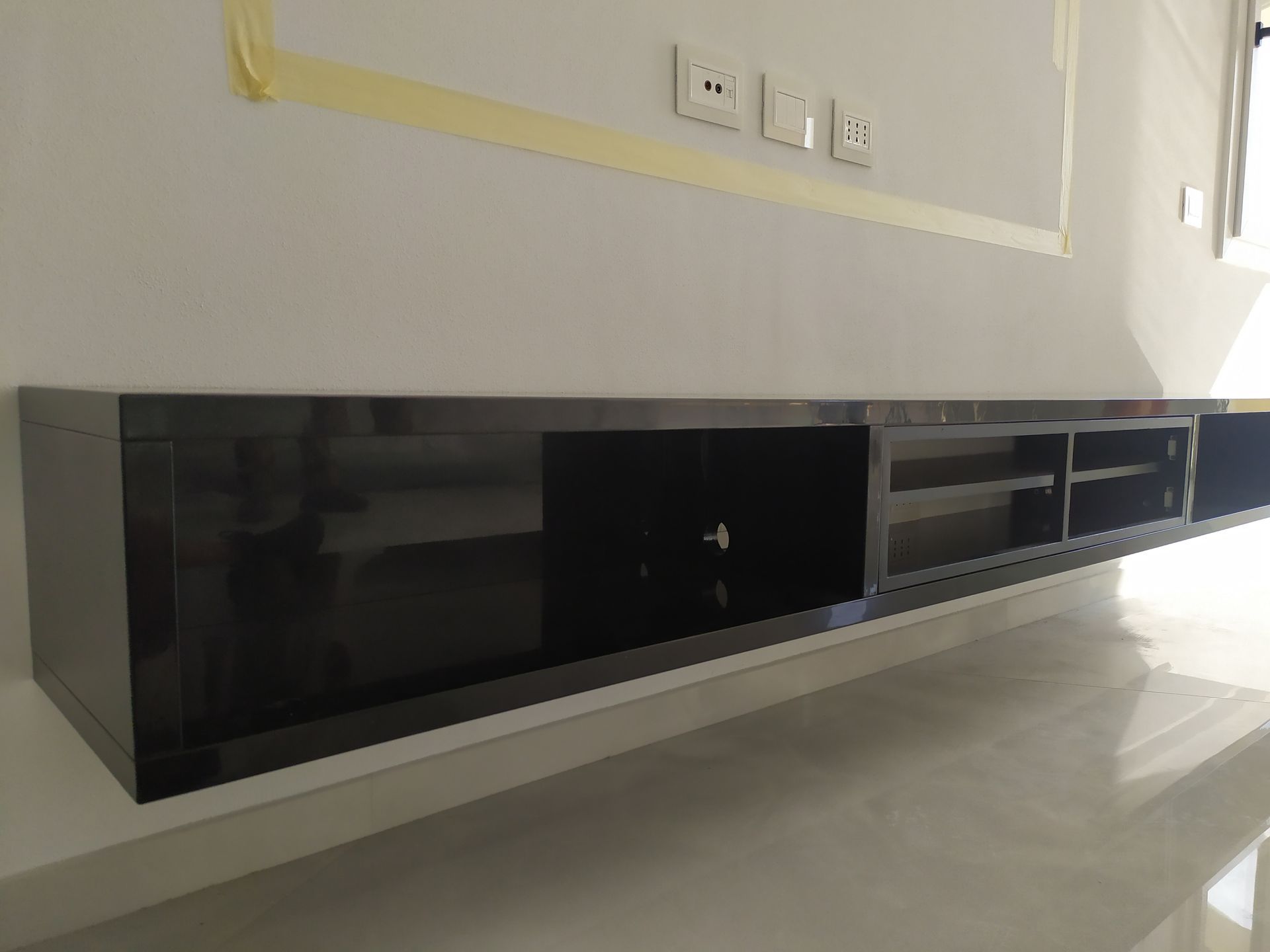 Un mobile porta TV nero è appeso alla parete del soggiorno.
