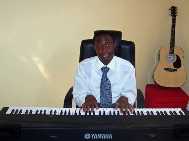 A man sits at a yamaha keyboard next to a guitar