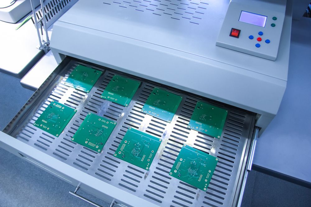 Electronics assembly machine processing green circuit boards on a conveyor tray