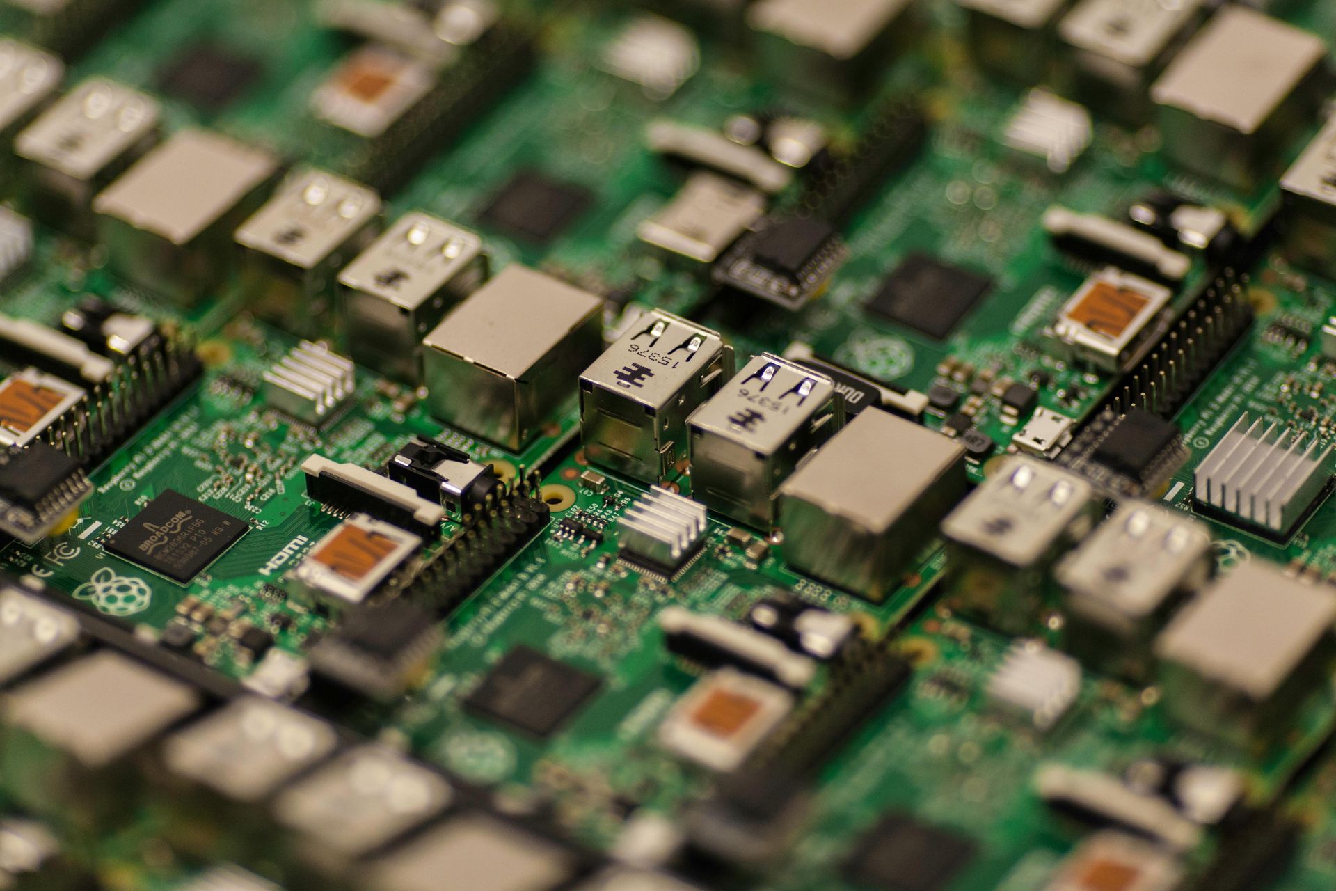 Close-up of green circuit boards with electronic components and USB ports on a production line