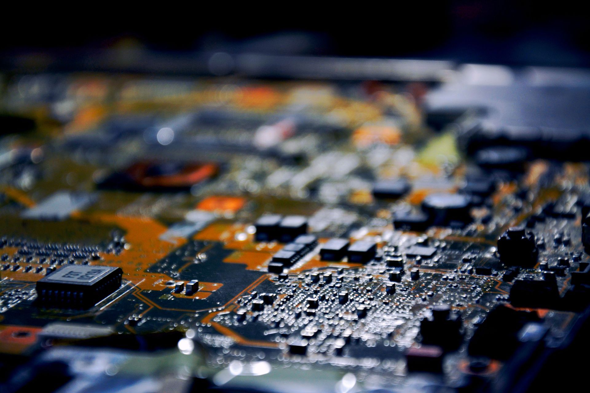 Close-up of a circuit board with orange traces and black components in shallow focus