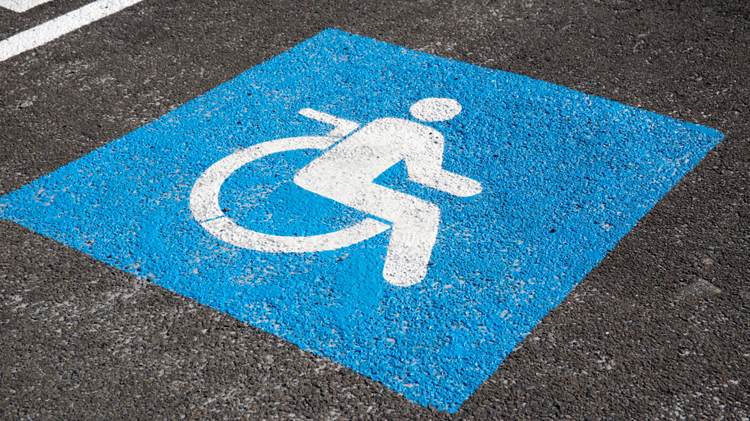 A handicapped sign is painted on the ground in a parking lot.