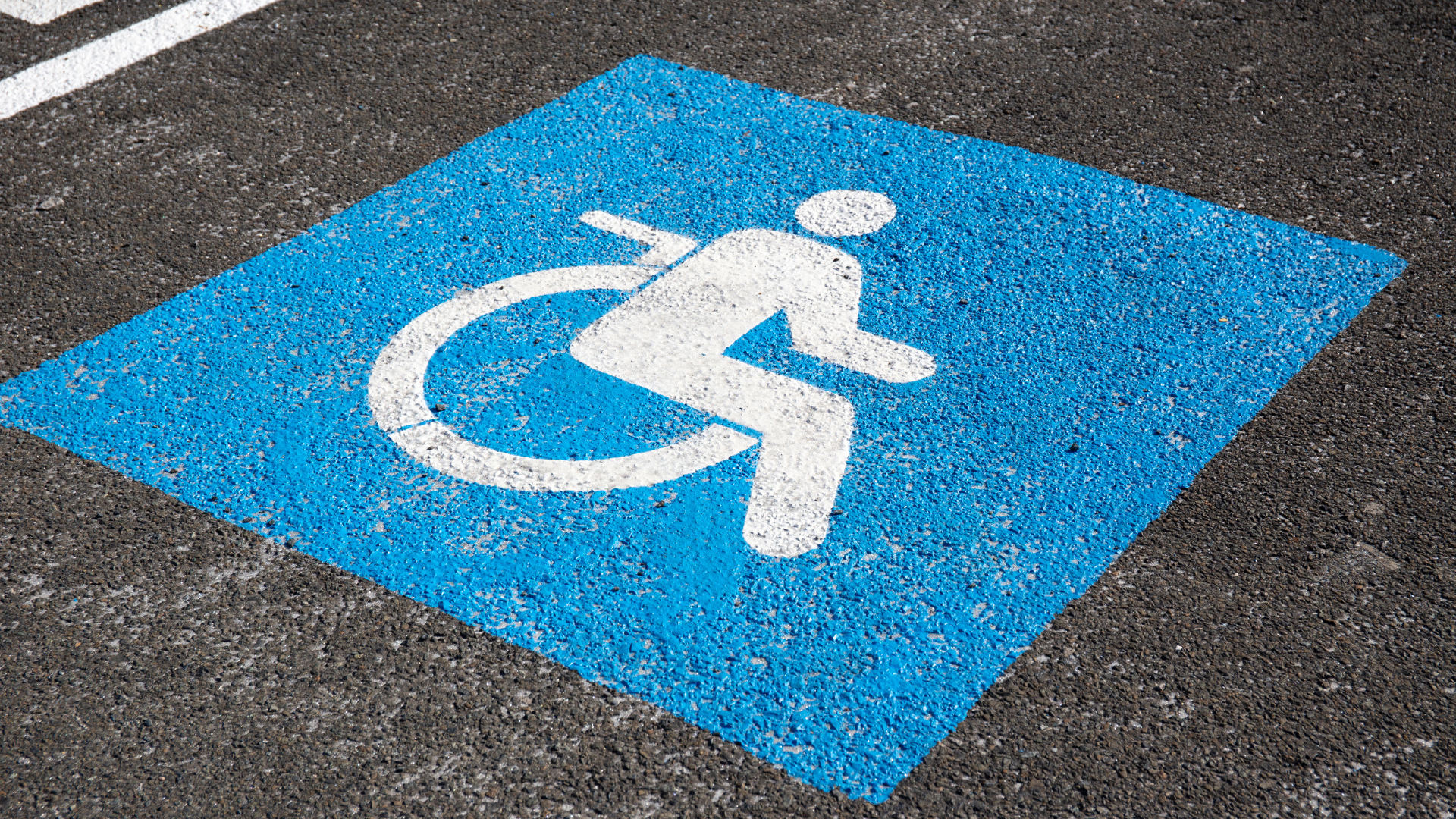 A handicapped sign is painted on the ground in a parking lot.