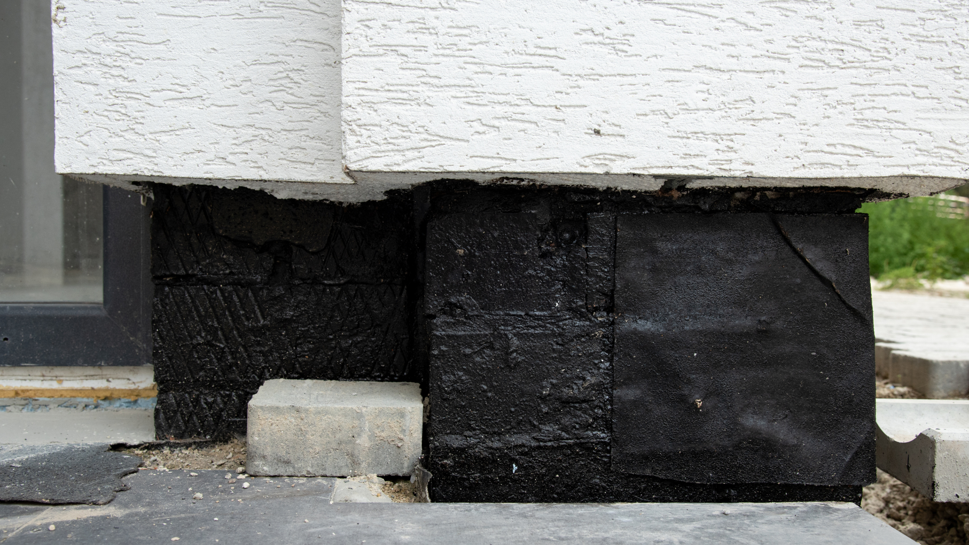 A black block is sitting on top of a white block on the side of a building.