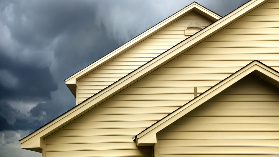 The roof of a house with a cloudy sky in the background.