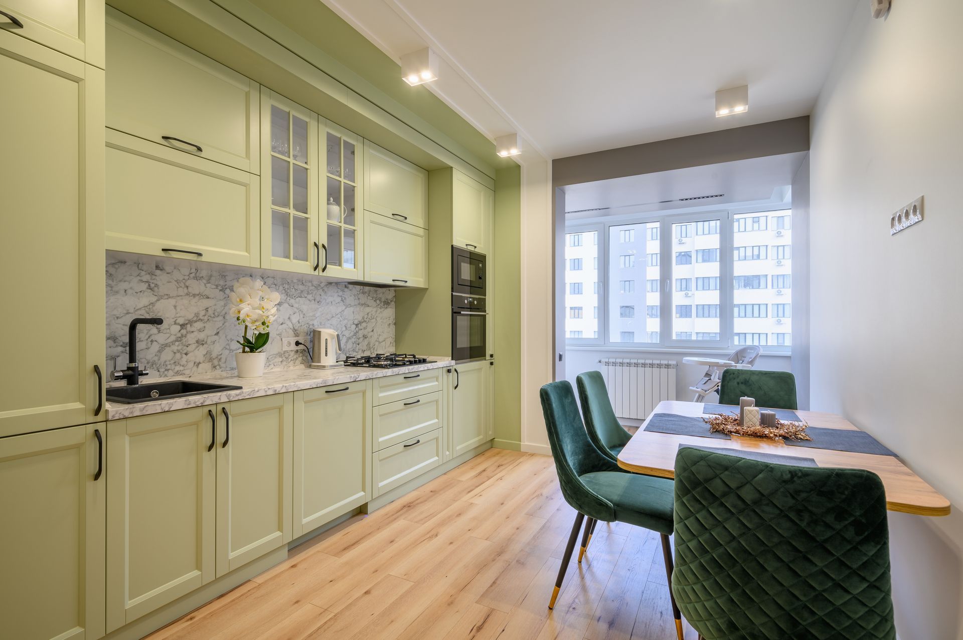 A kitchen with green cabinets and a dining table with green chairs.