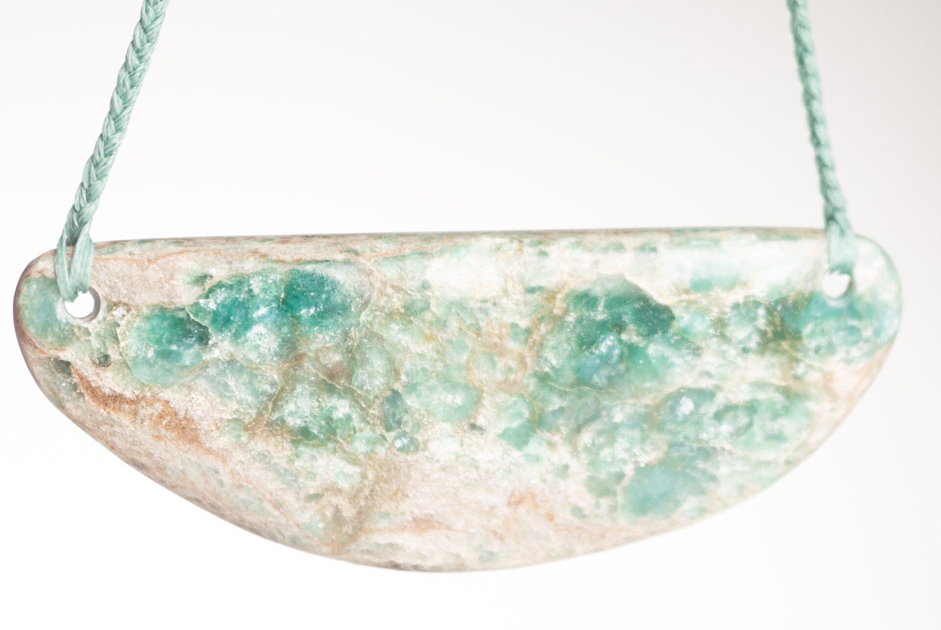 A close up of a necklace with a blue pendant on a white background.