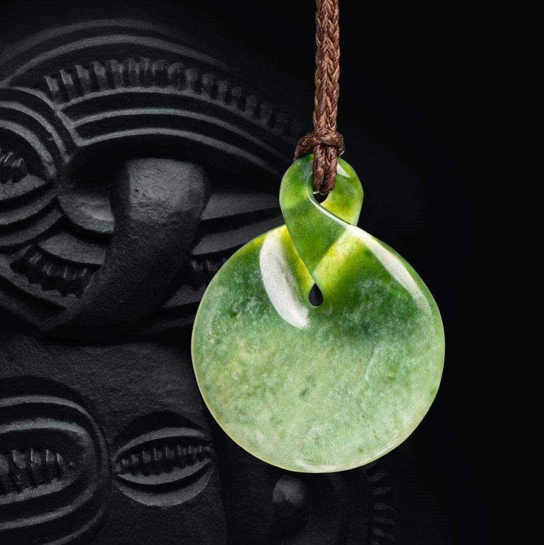 A green pendant is hanging from a brown string