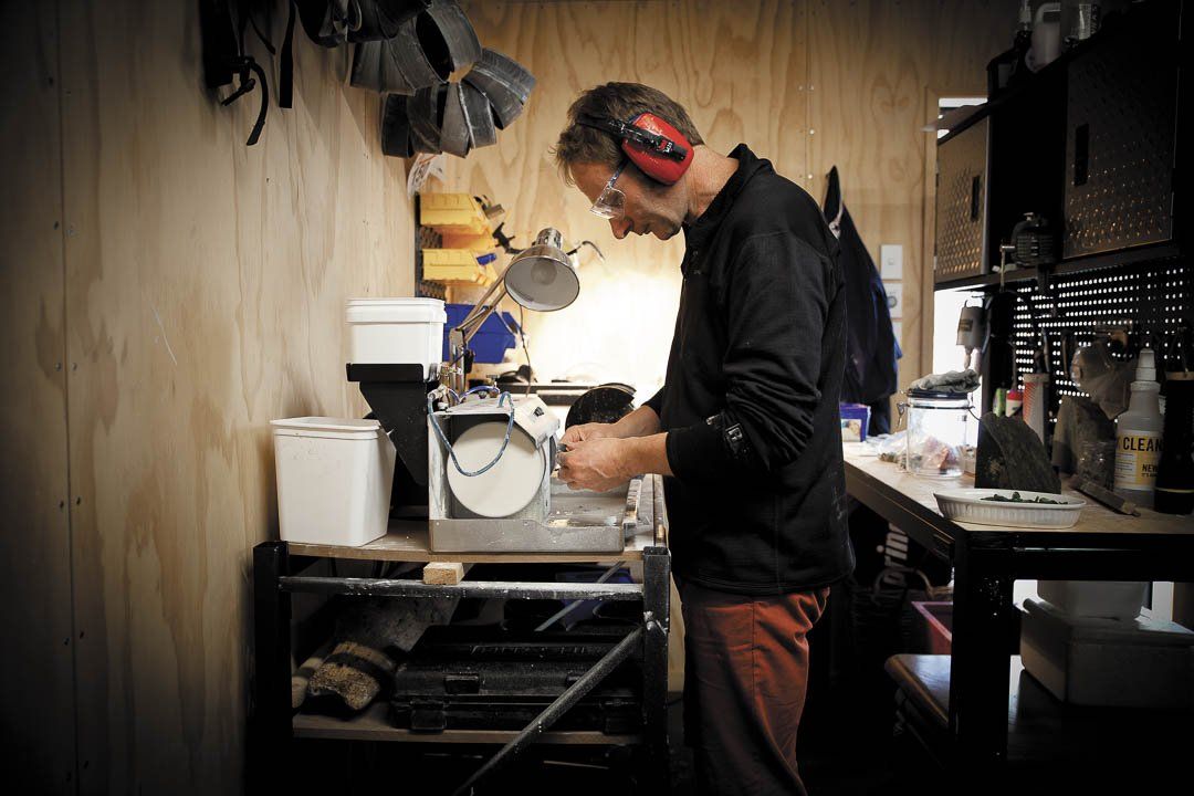 A man wearing ear muffs is working on a machine in a workshop.