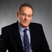 A man in a suit and tie is sitting down and smiling.