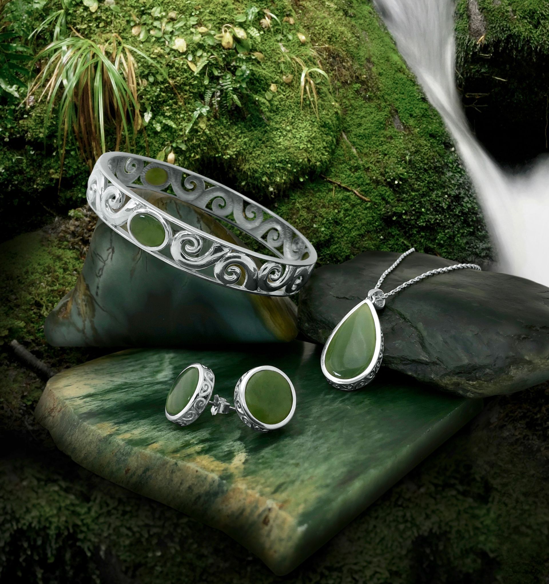 A bracelet ring and necklace are sitting on a rock