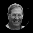 Smiling man with glasses in front of a black background.