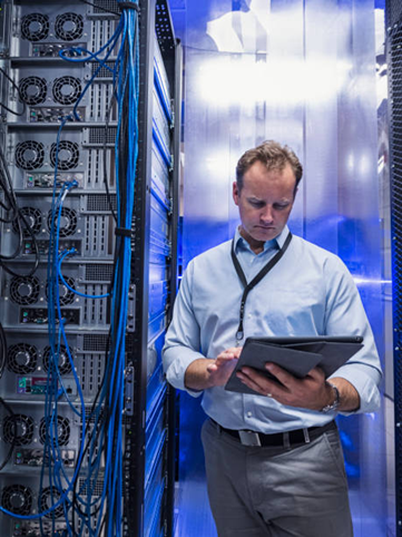 Man in server room, checking tablet, blue data cables, servers in the background.