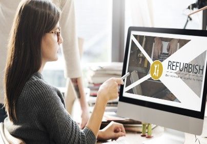 A woman is sitting at a desk looking at a computer screen.