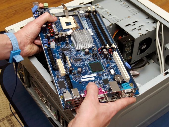 Close-up picture of a technician holding a motherboard before performing computer repair services