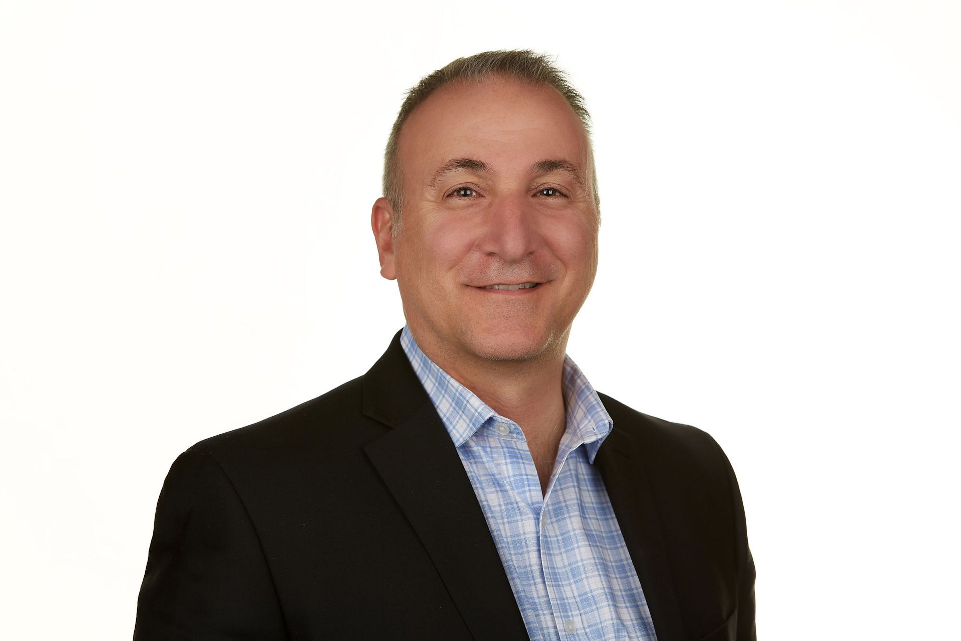 A man in a suit and blue shirt is smiling for the camera.