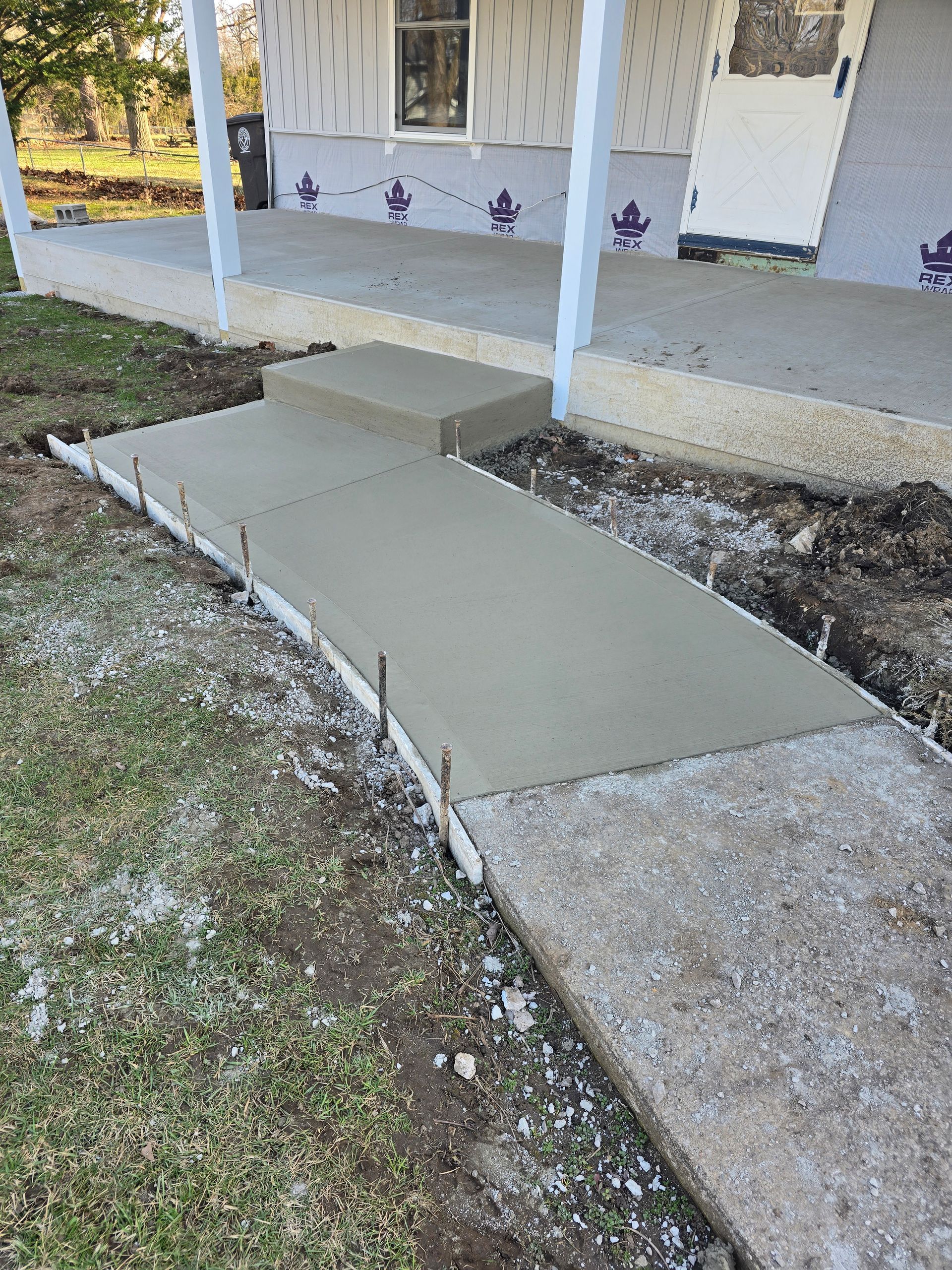 A concrete walkway is being built in front of a house.