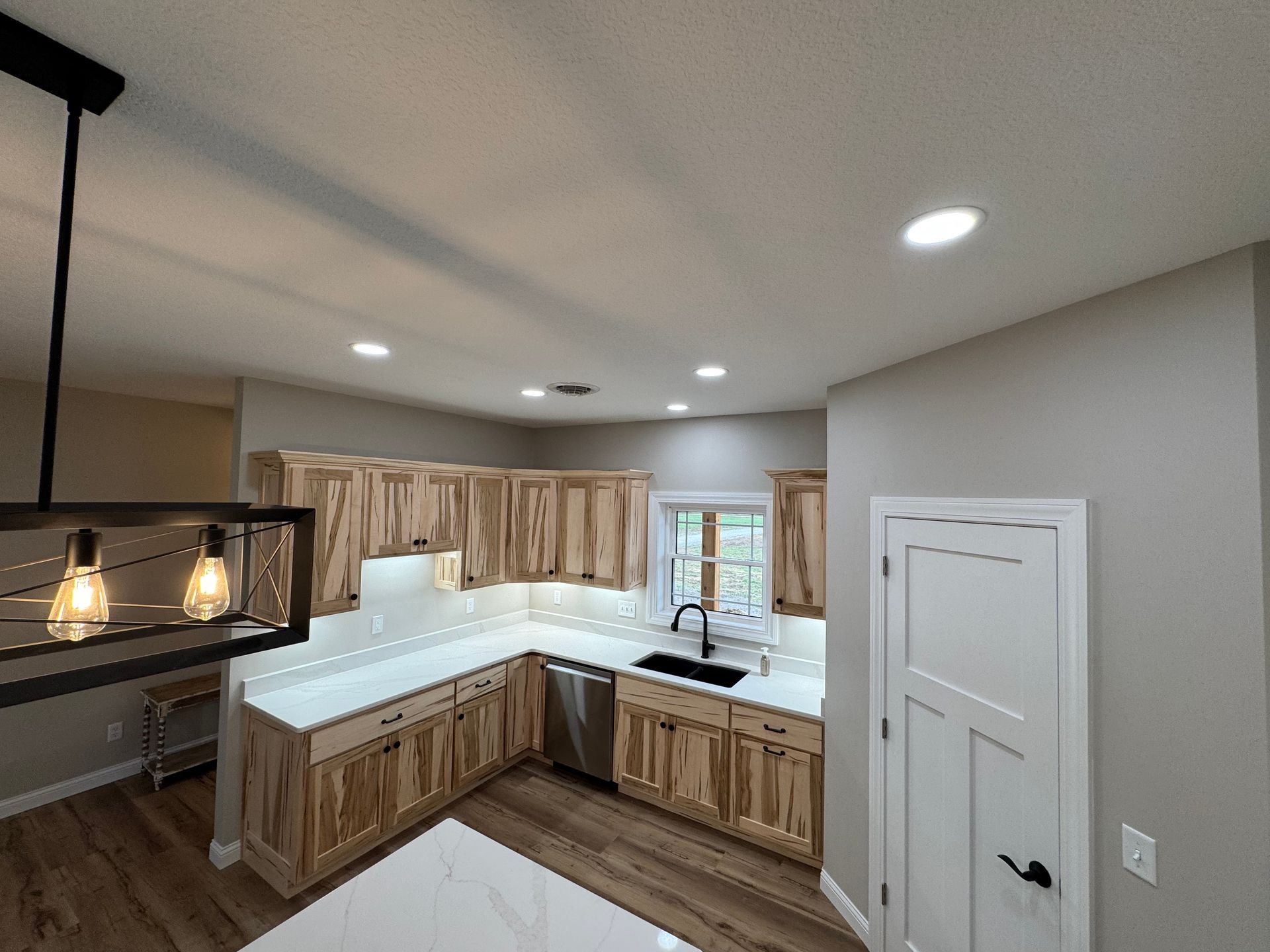 A kitchen with wooden cabinets , white counter tops , and a sink.