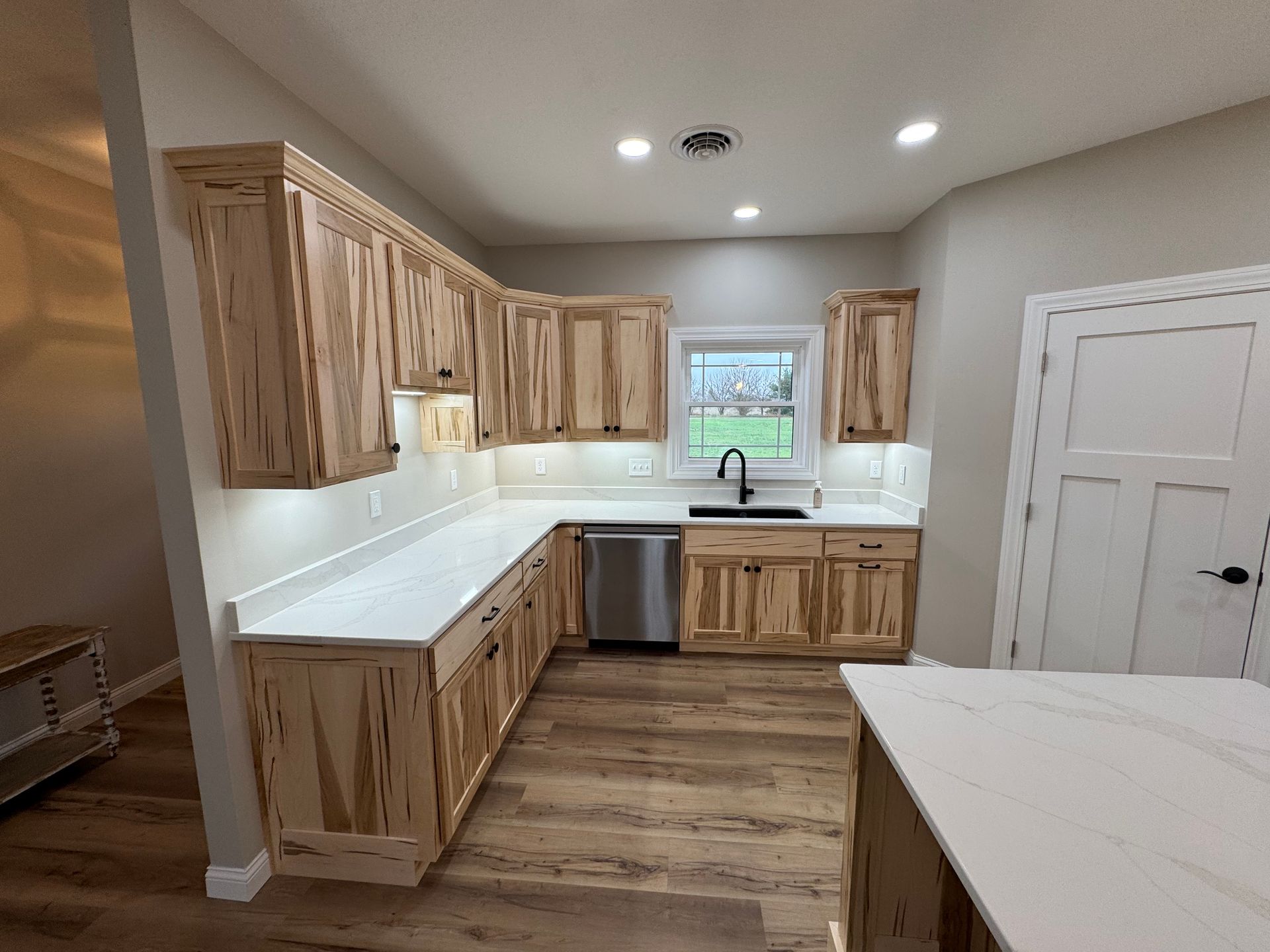 A kitchen with wooden cabinets , white counter tops , and stainless steel appliances.