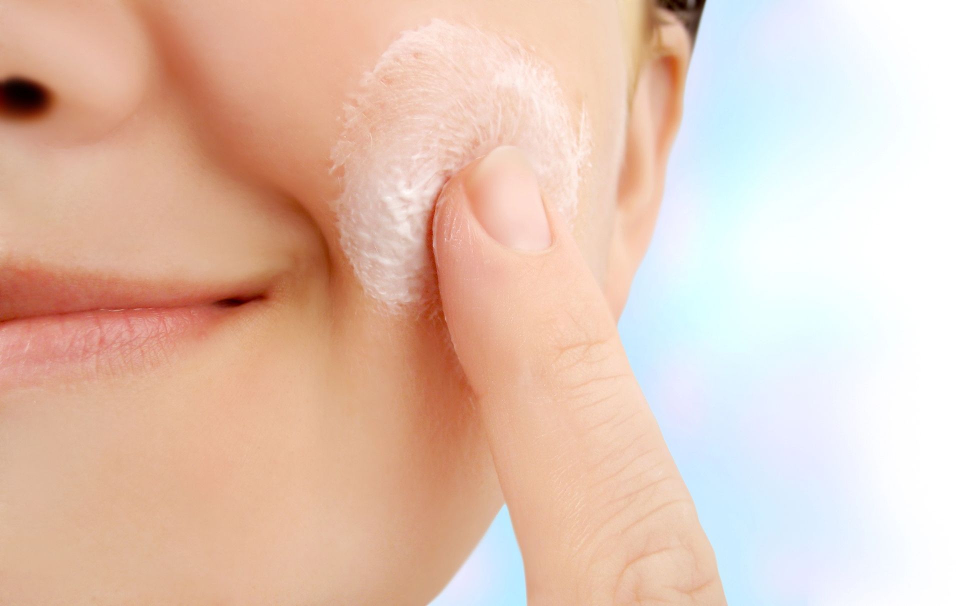 Persona che applica la crema sulla guancia con la punta delle dita.