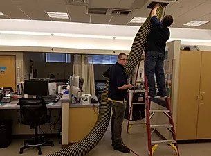 man on a ladder, cleaning an air duct
