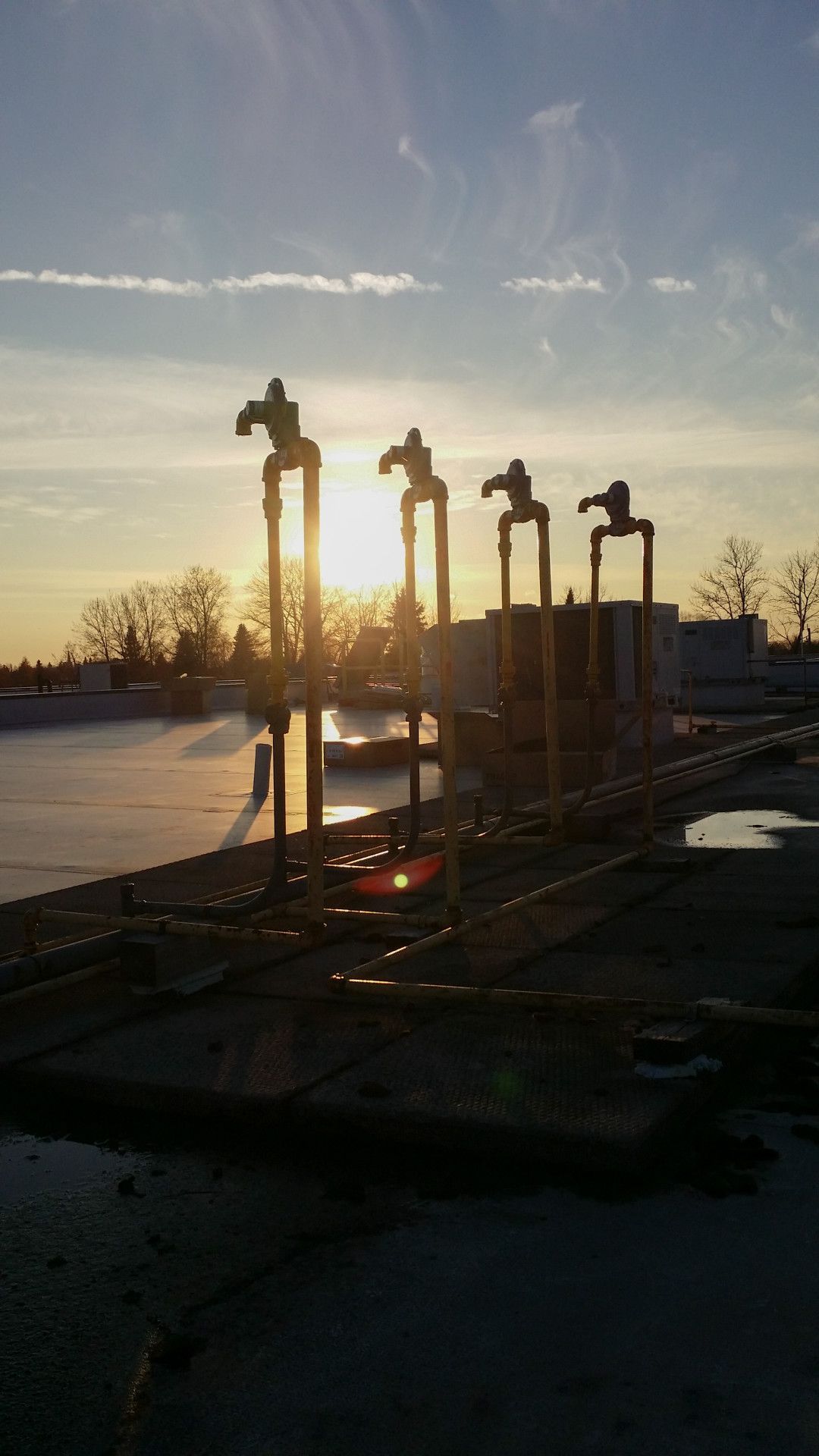 Sunrise behind silhouetted industrial pipes on a frozen landscape.