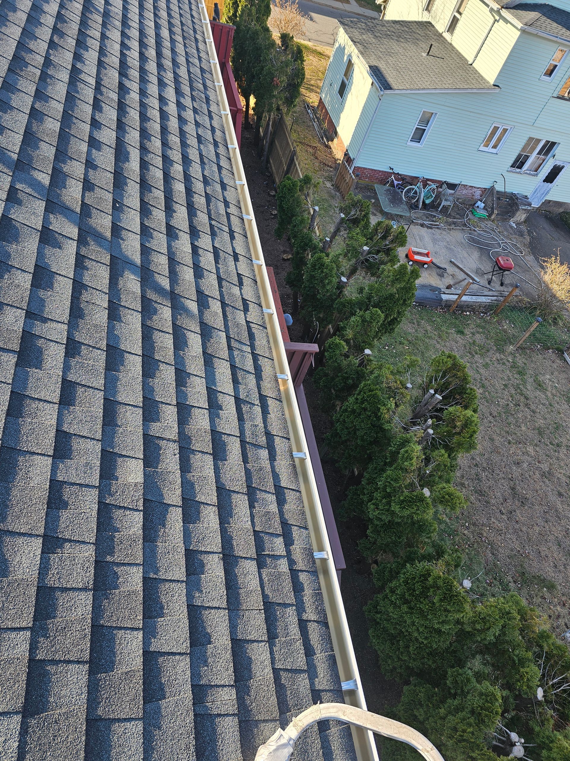 A close up of a gutter on a roof next to a window.