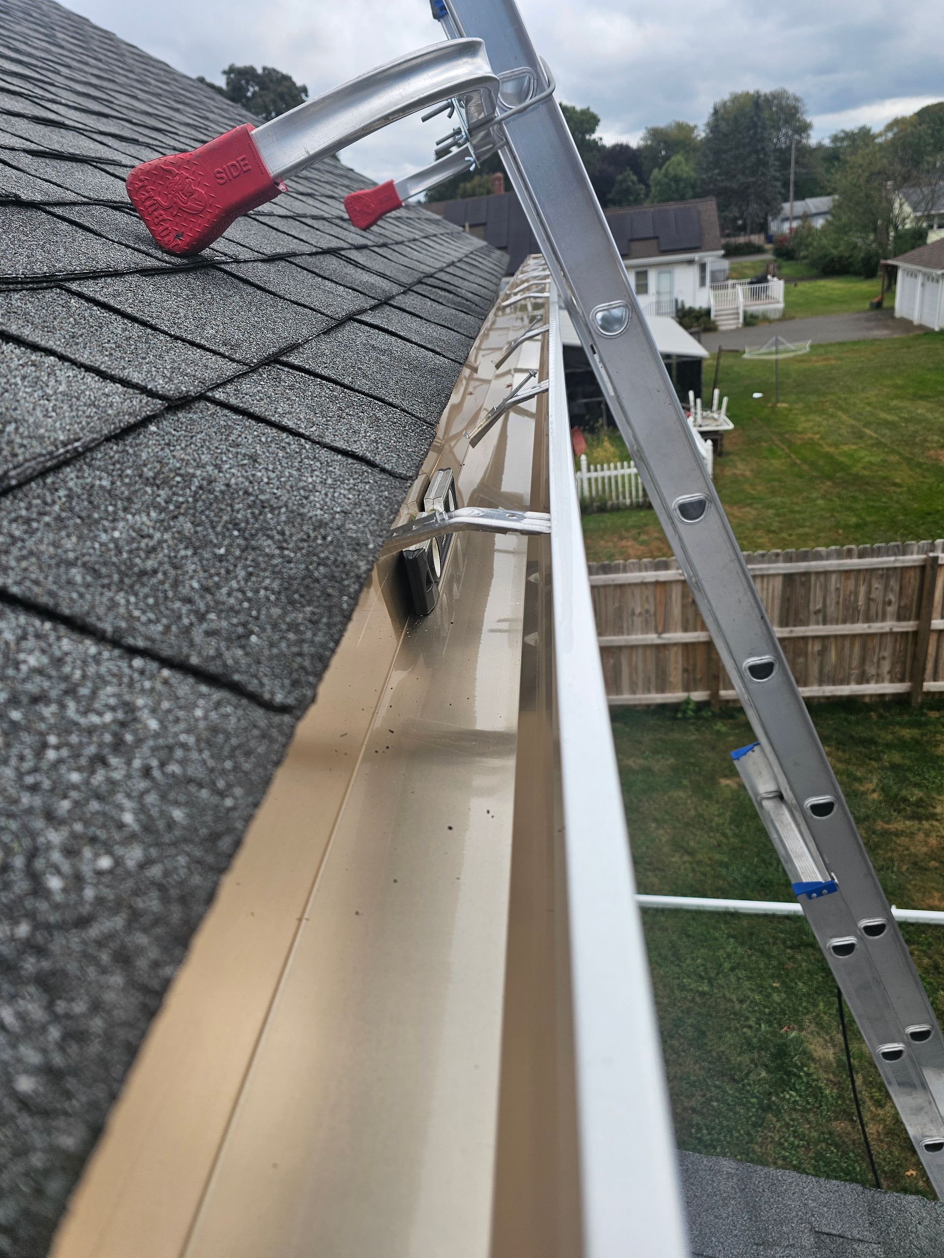 A white gutter with a black roof in the background