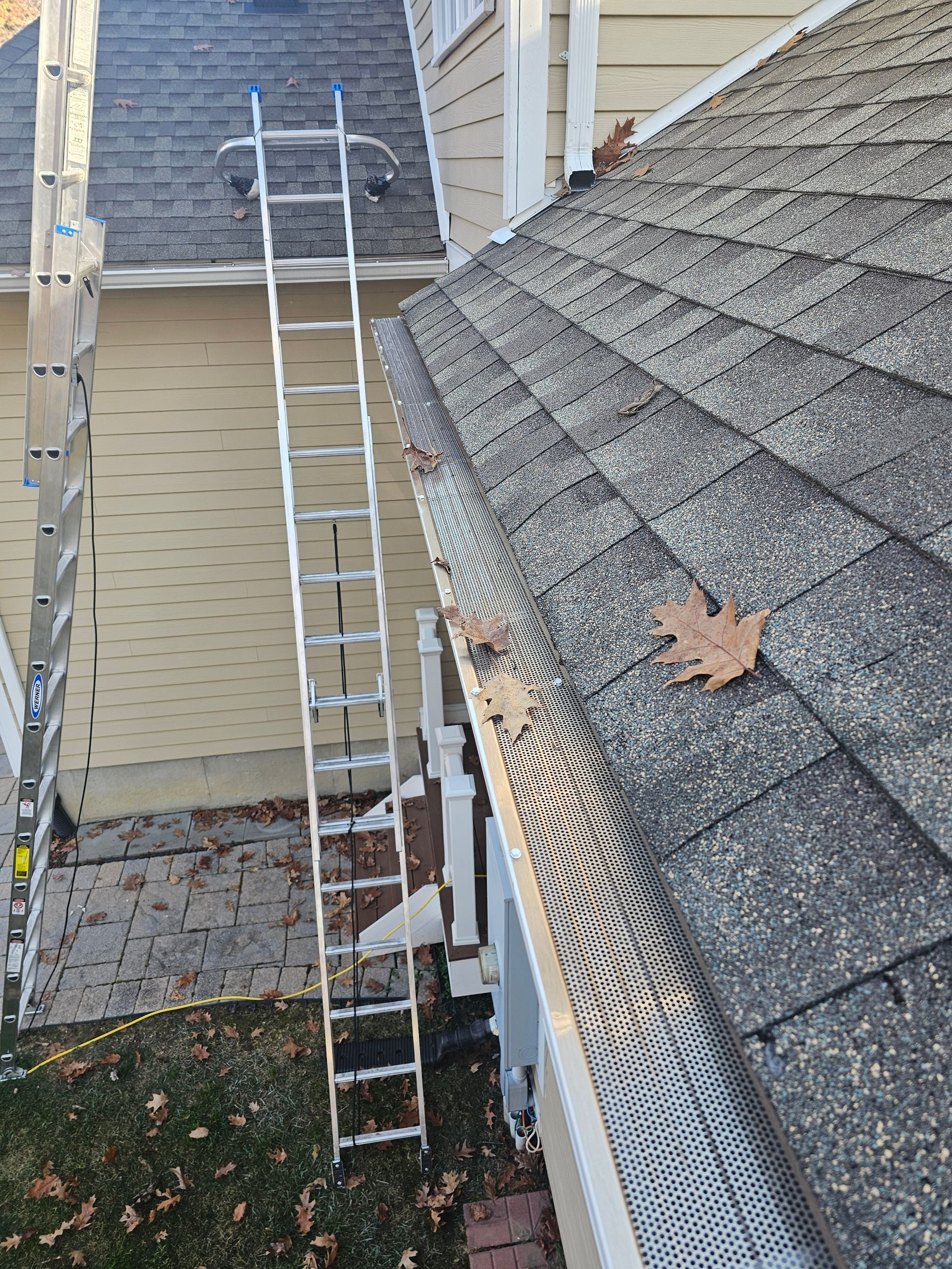 A white gutter on the side of a building with a red roof.