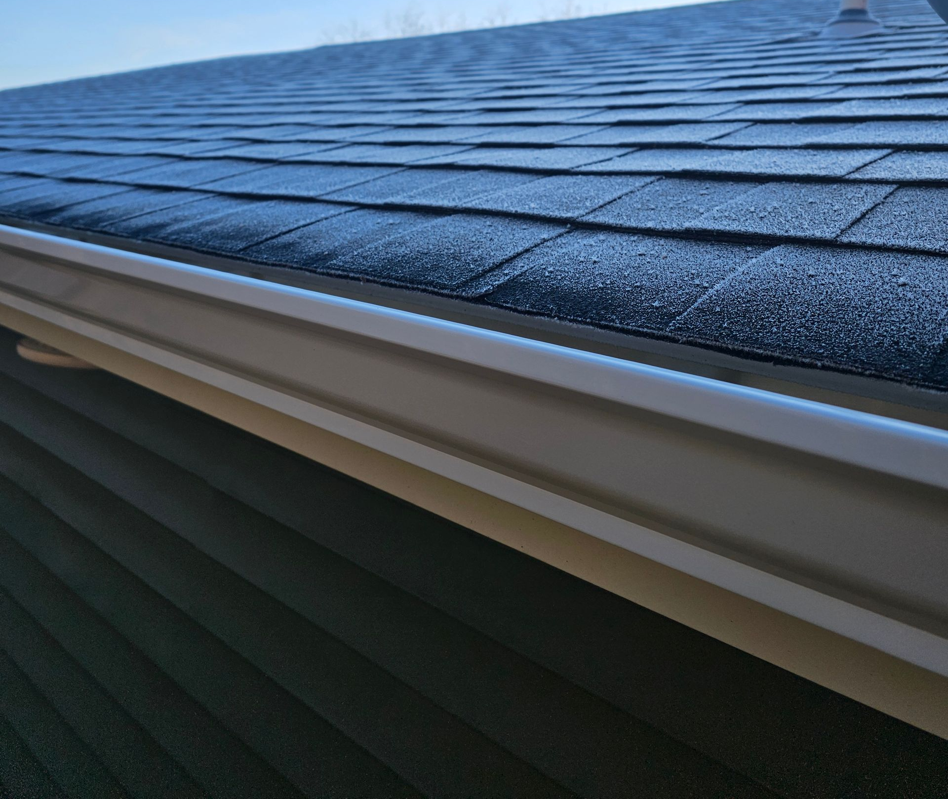 A close up of the roof of a house with a blue sky in the background.