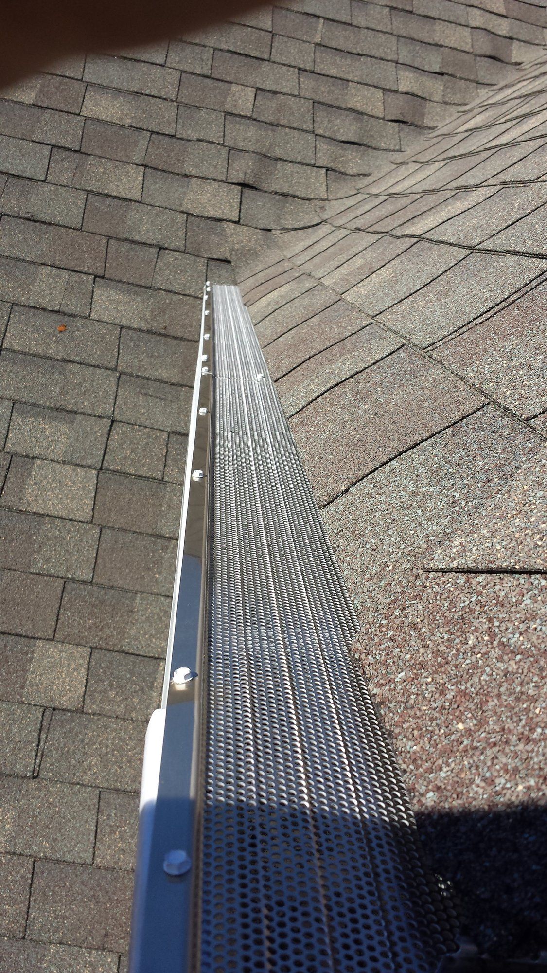 A close up of a gutter on a roof next to a window.