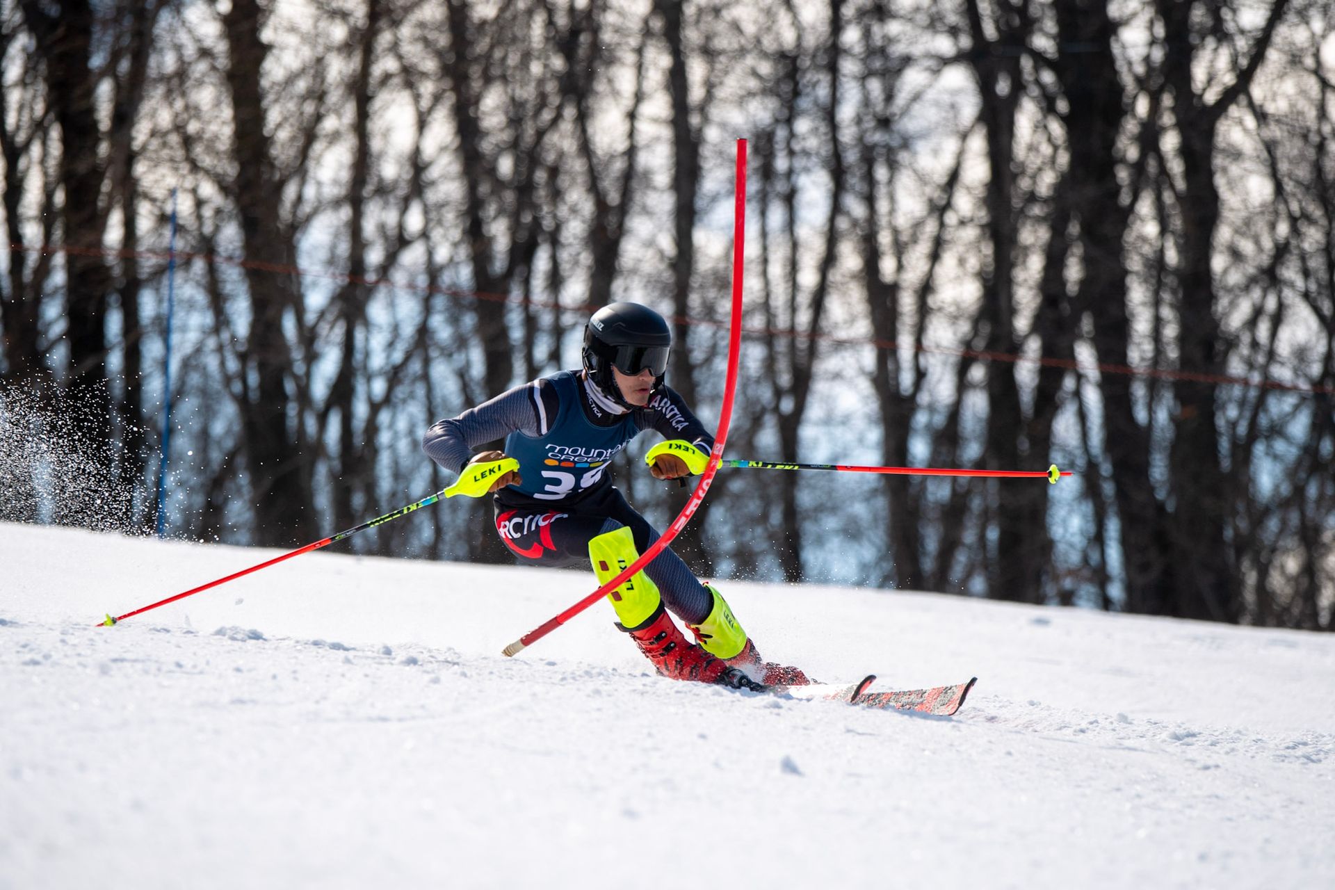 Skier in a race, carving down a snow-covered slope, passing a gate.