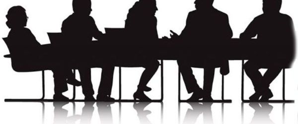 Silhouetted people seated around a table, possibly in a meeting.