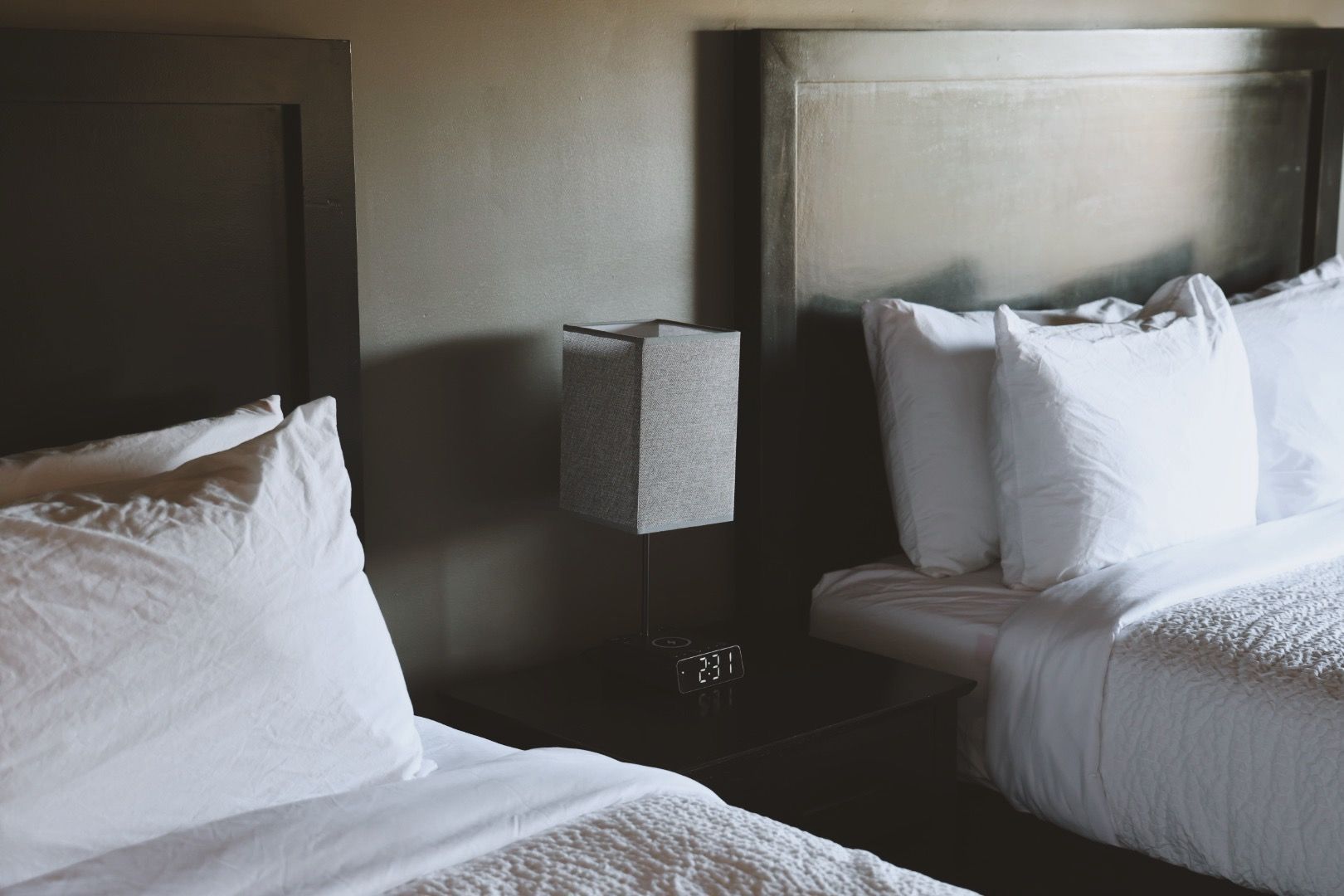 A hotel room with two beds and a lamp.