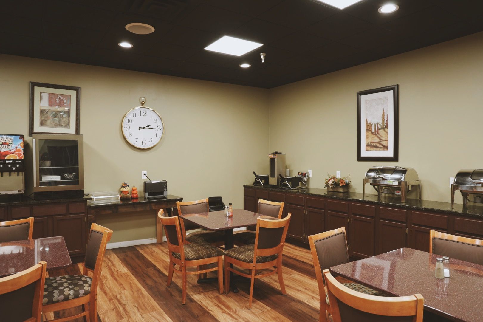 A dining room with tables and chairs and a clock on the wall.