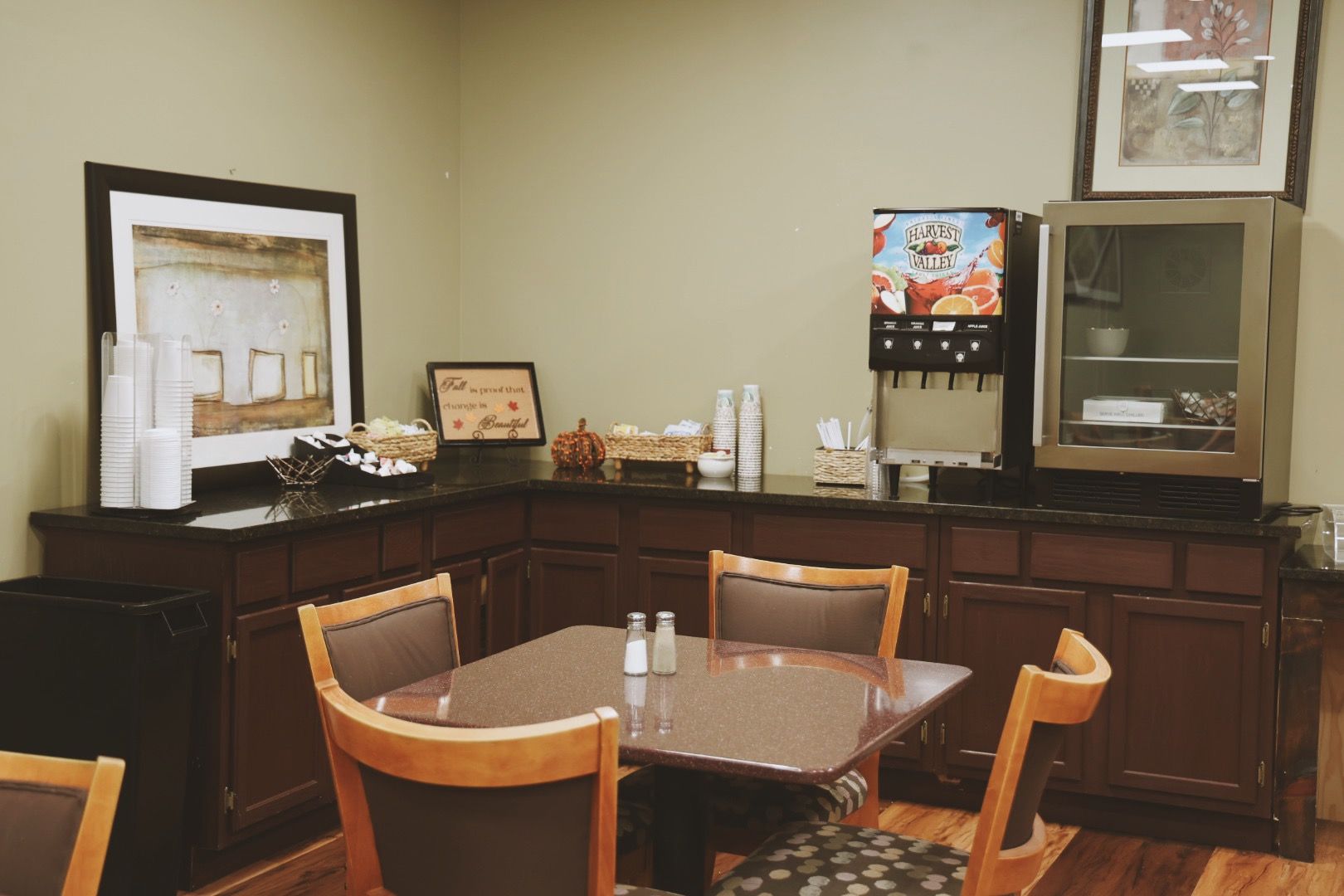 A dining room with a table and chairs and a drink dispenser.