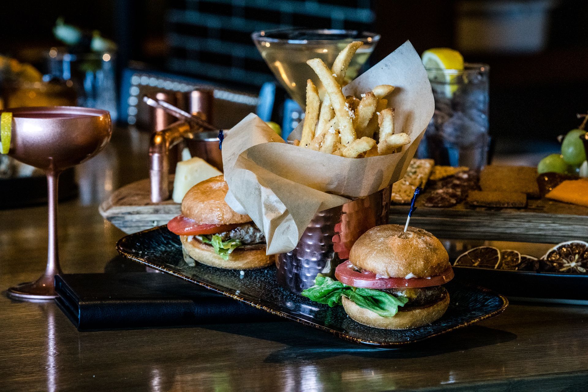 Two hamburgers and french fries on a tray on a bar.