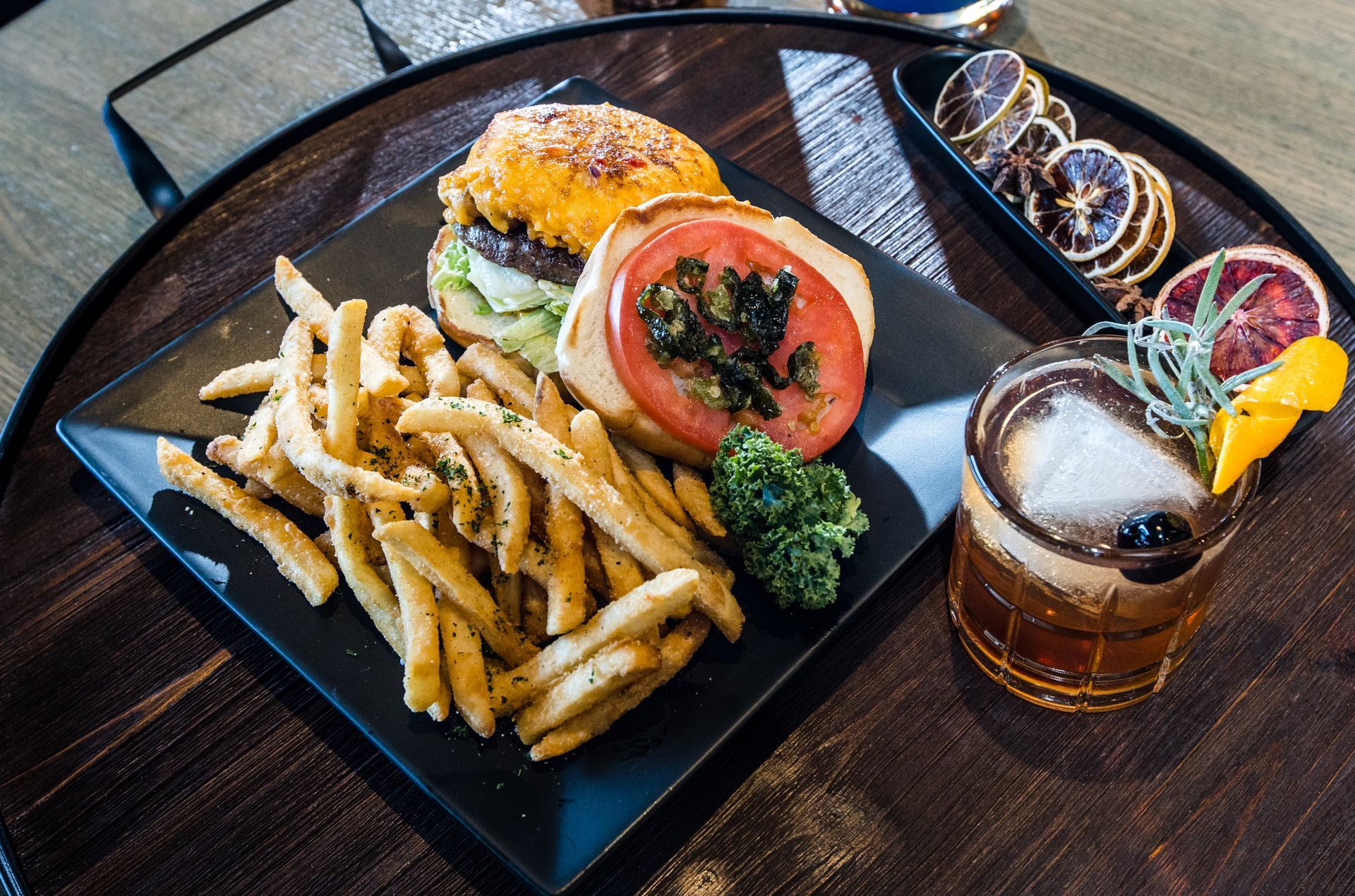 A plate of food with french fries , a hamburger and a drink on a table.