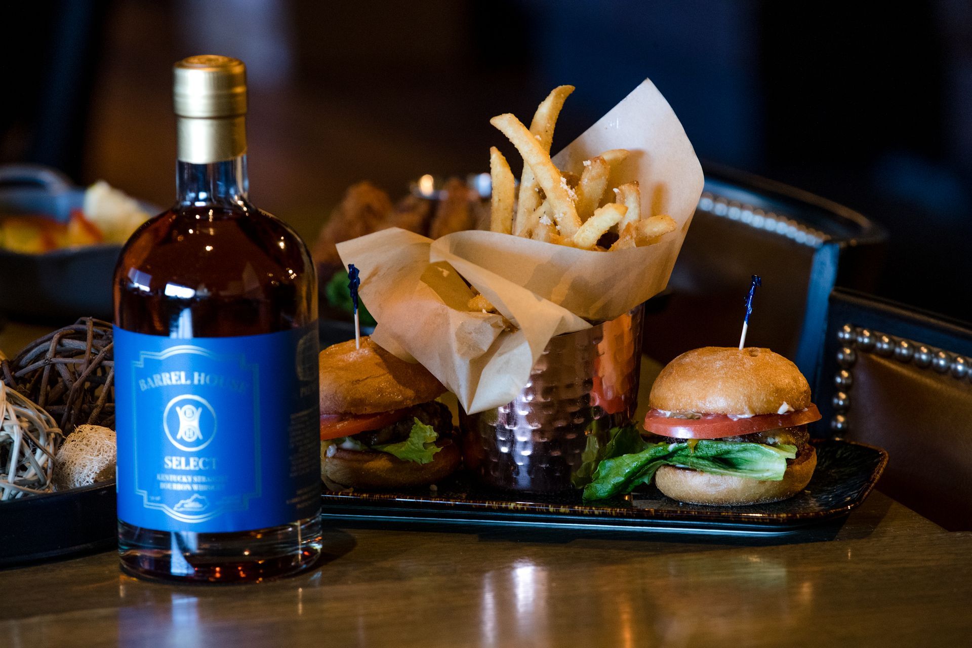 A bottle of whiskey next to a tray of hamburgers and french fries