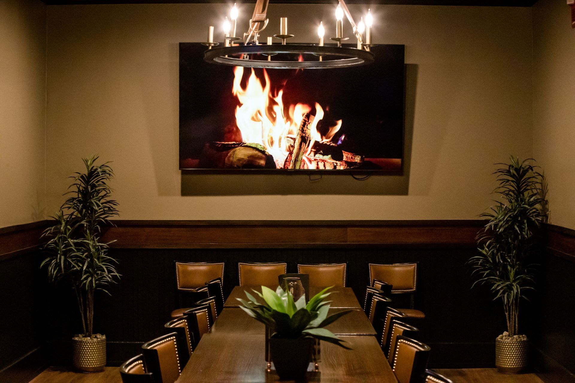 A conference room with a long table and chairs and a fireplace on the wall.
