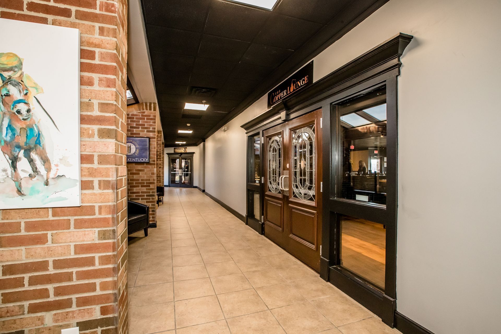 A long hallway with a brick wall and a painting on the wall.