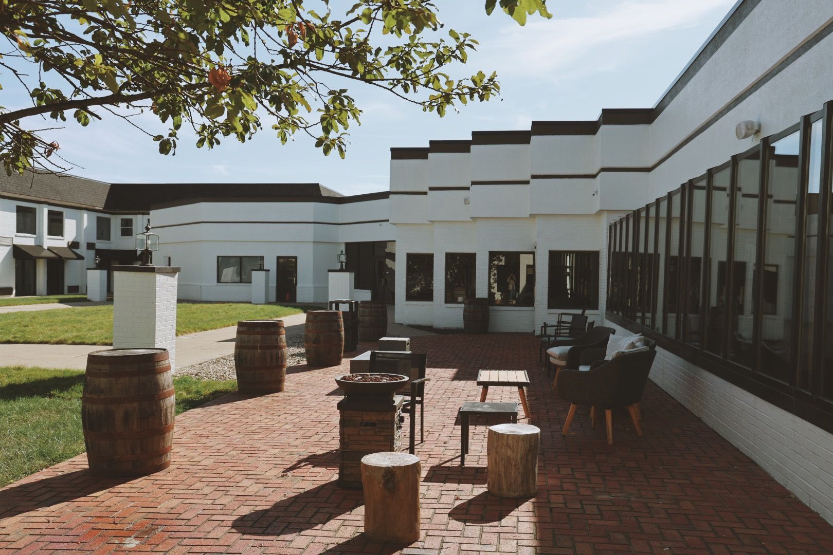 A brick courtyard with barrels and tables in front of a building.