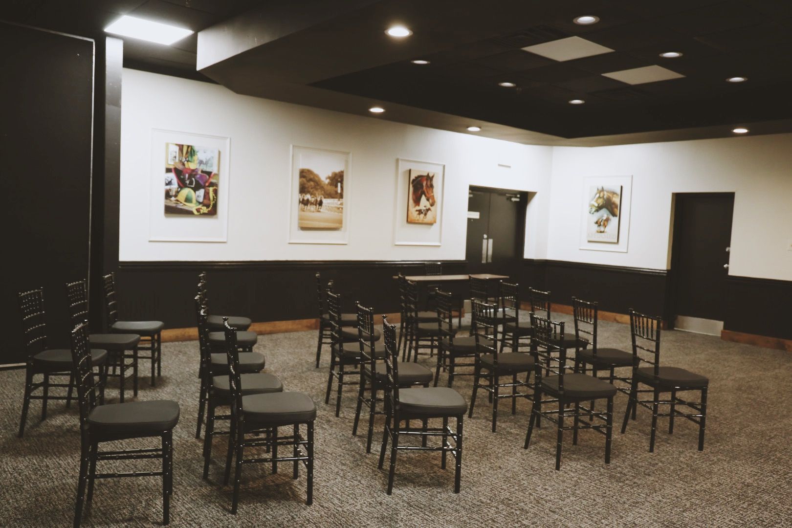 Rows of chairs are lined up in a room with paintings on the wall.
