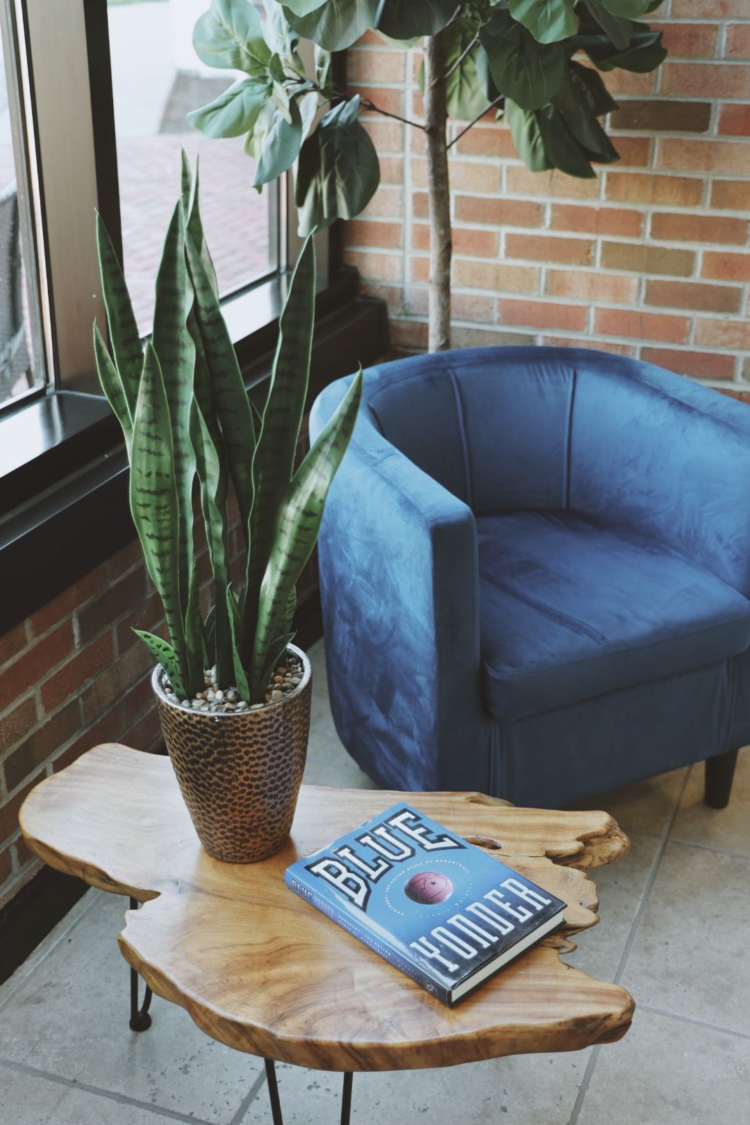 A blue chair is sitting next to a wooden table with a book on it.