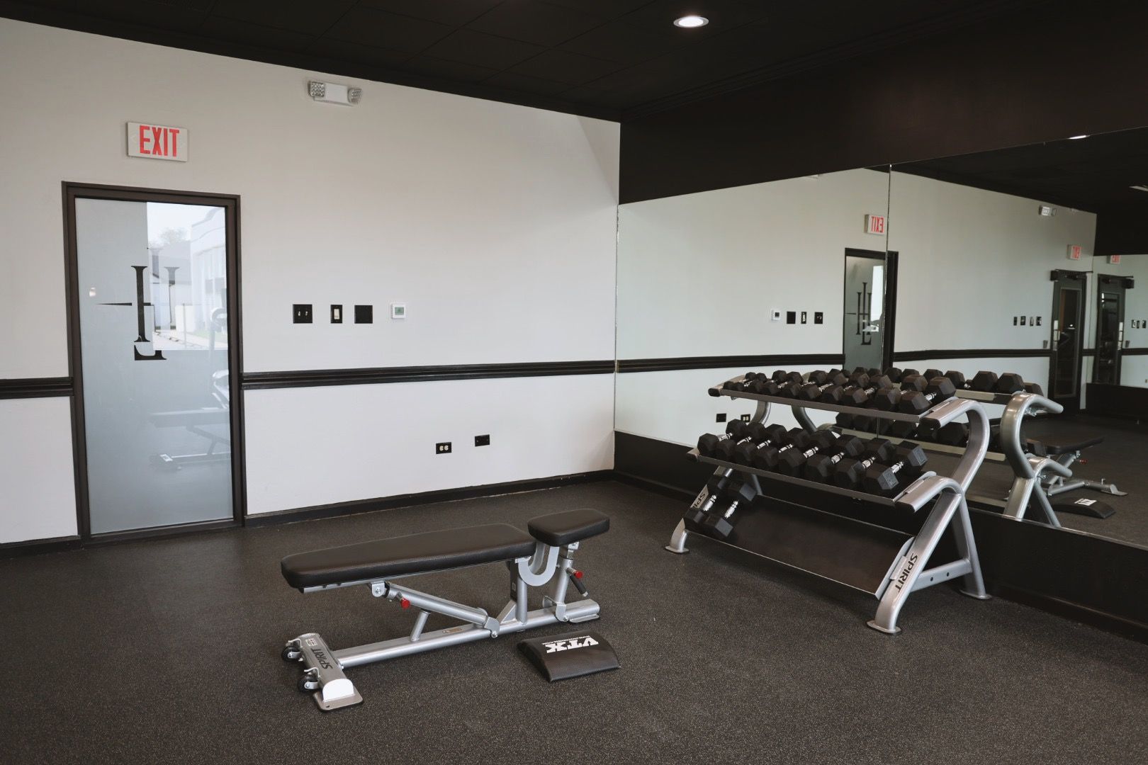 A gym with a bench and dumbbells in it