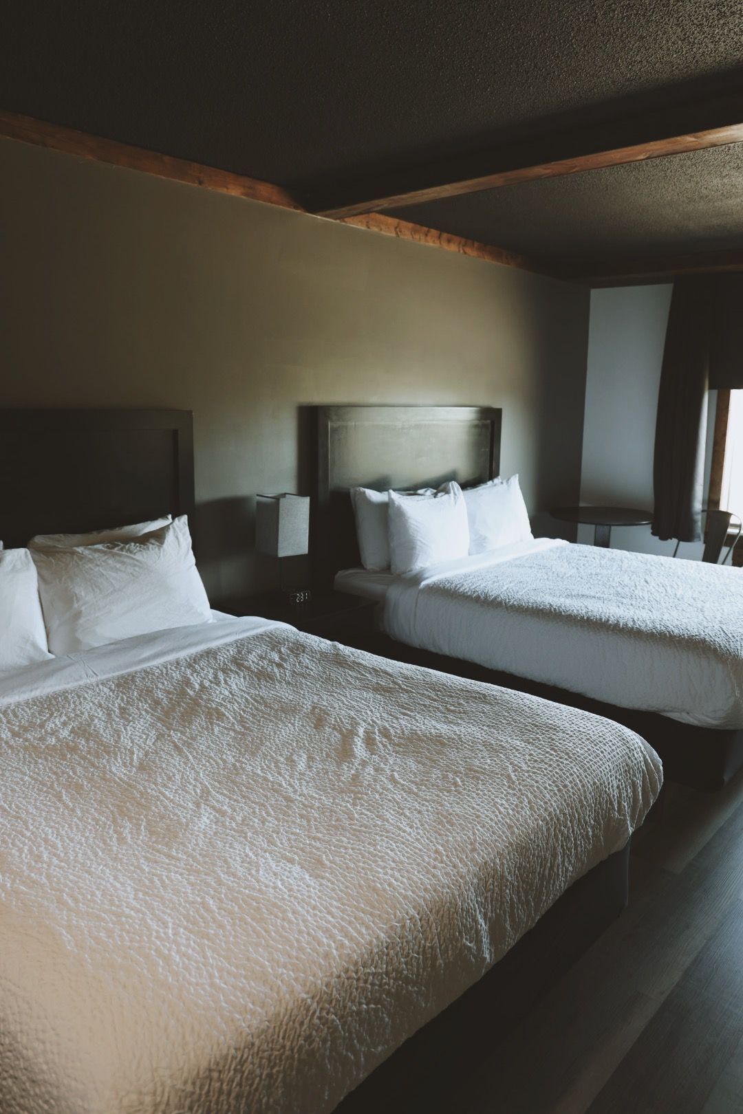 A hotel room with two beds and a window.