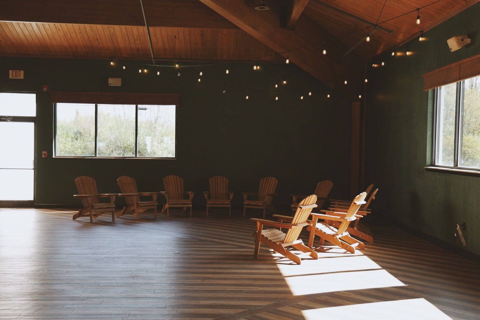 A row of wooden chairs are sitting in a room with a wooden floor.