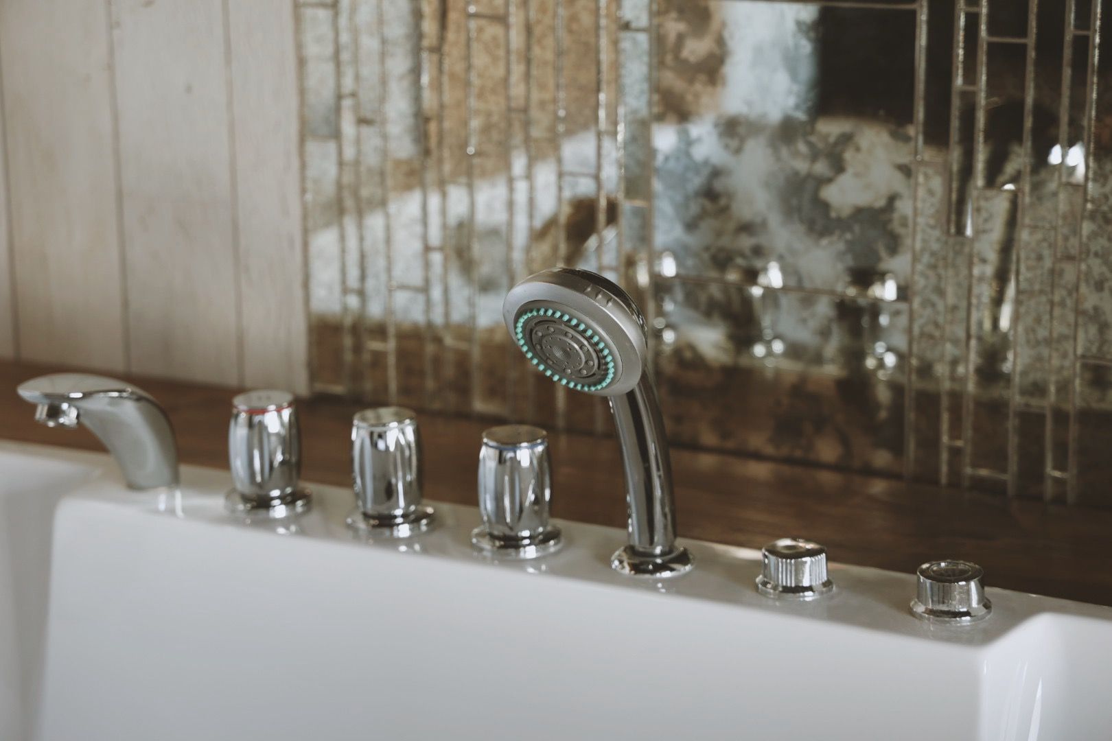 There is a shower head on the side of a bathtub.