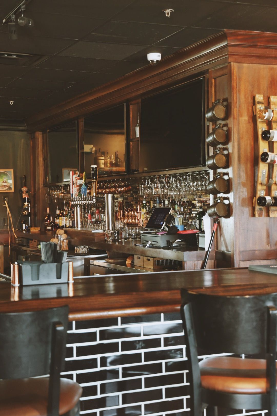 A bar in a restaurant with a wooden bar and chairs.