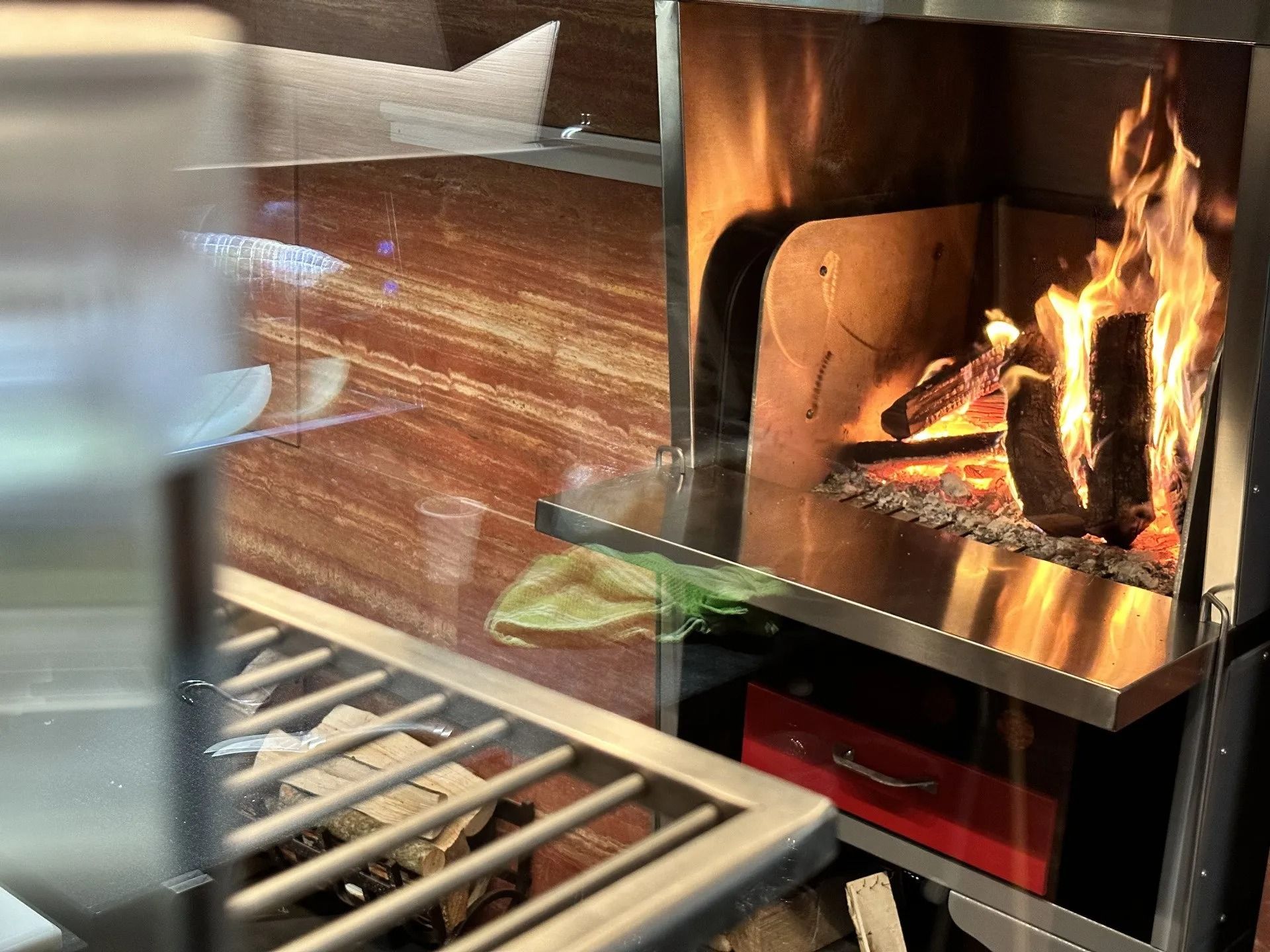 Fuoco che arde in un camino in acciaio inossidabile. Le fiamme illuminano l'interno metallico.